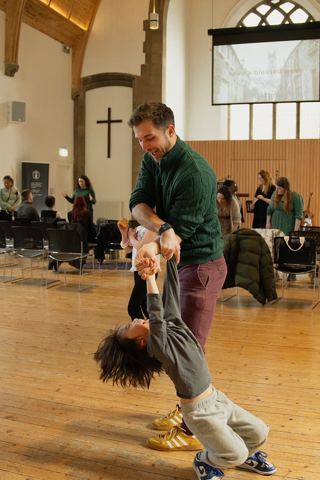 A C3 Kids leader swinging a delighted child by the arms in the church hall