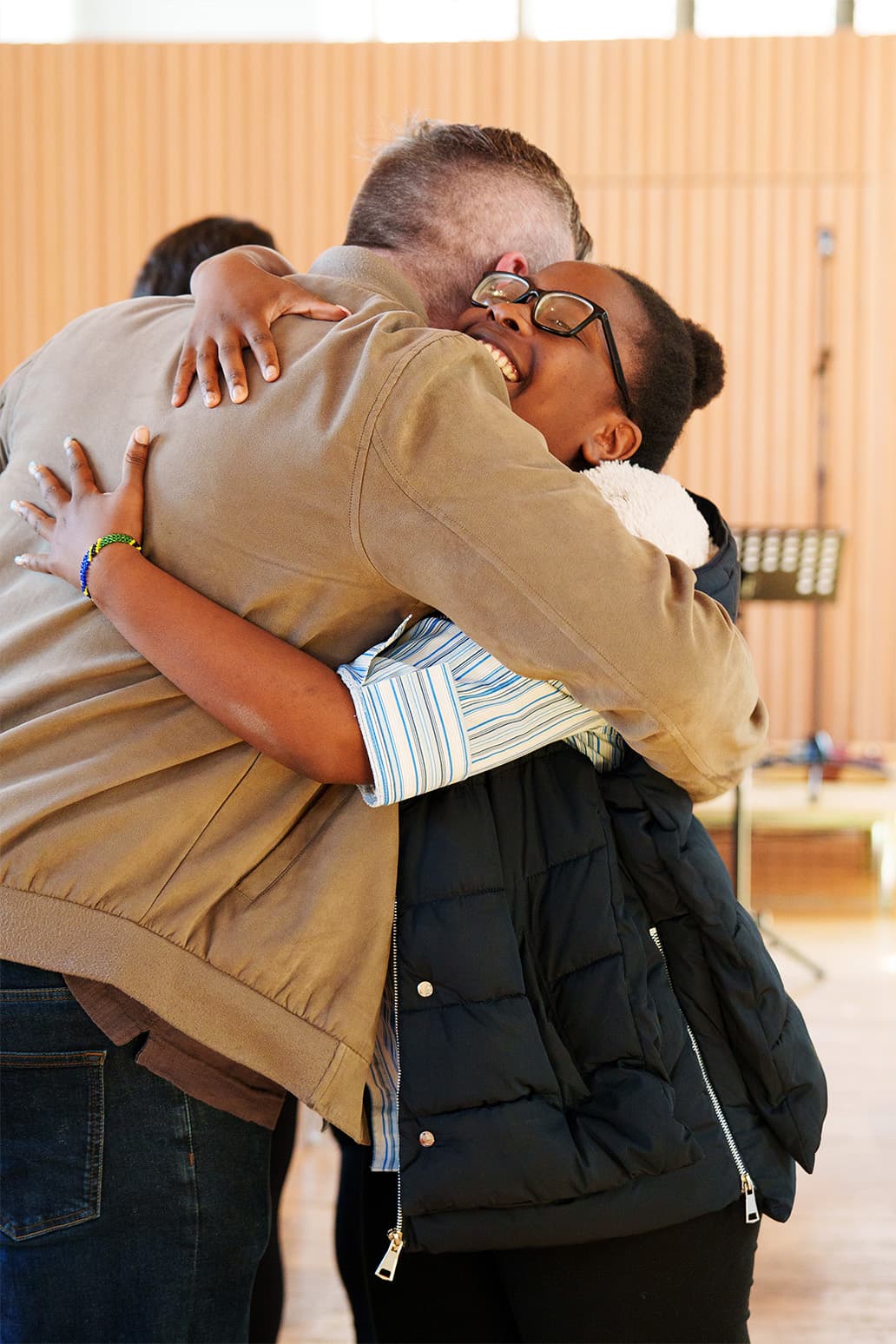 Two friends greeting each other with a hug at church