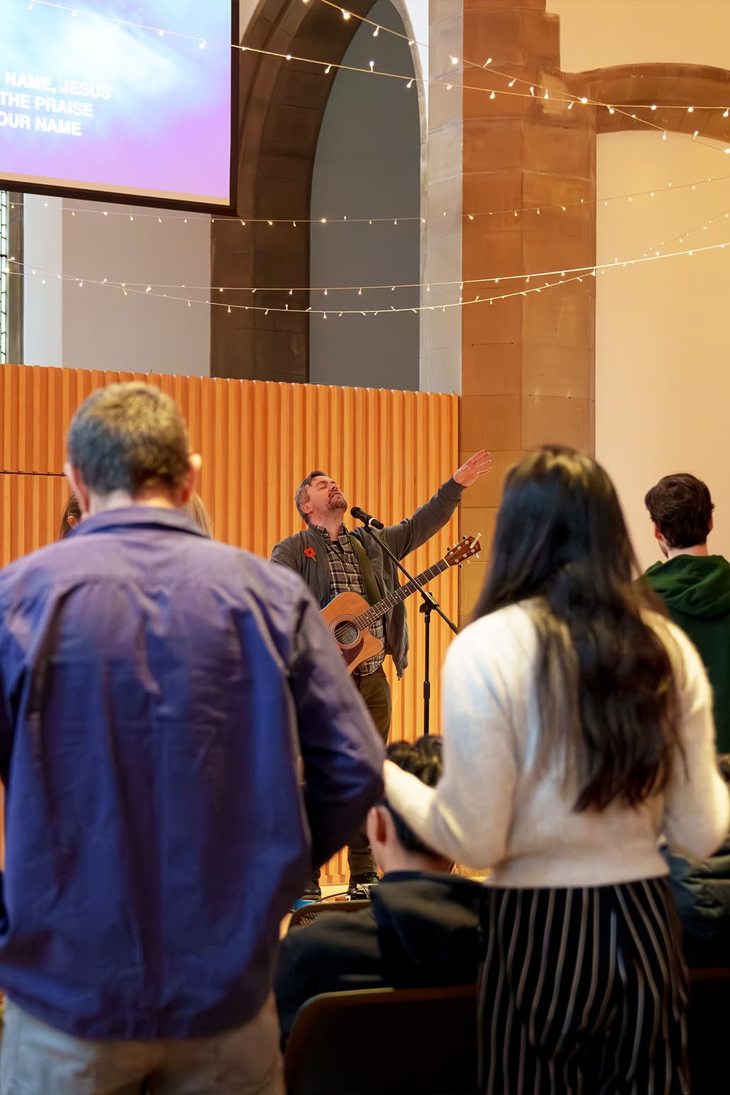 The congregation standing in worship in the sunlit hall at Greyfriars Charteris Centre
